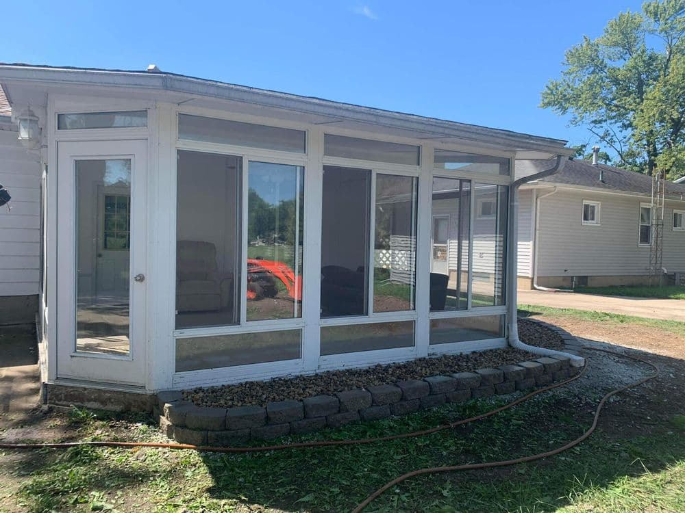 Bright, modern sunroom with large windows and landscaped exterior in residential setting.