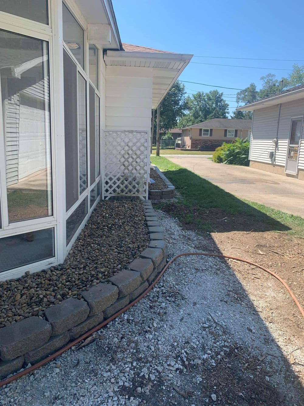 Landscaped side yard with rocks, stones, and gravel near a residential home exterior.