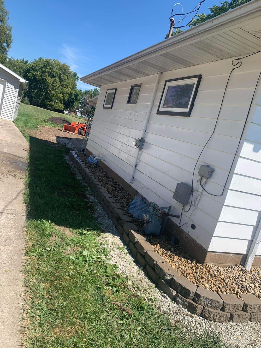Side view of a house with gravel landscaping and a stone border, showcasing lawn care.