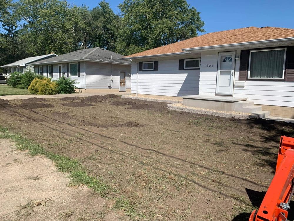 Residential landscaping project with freshly cleared ground in front of homes, ready for planting.
