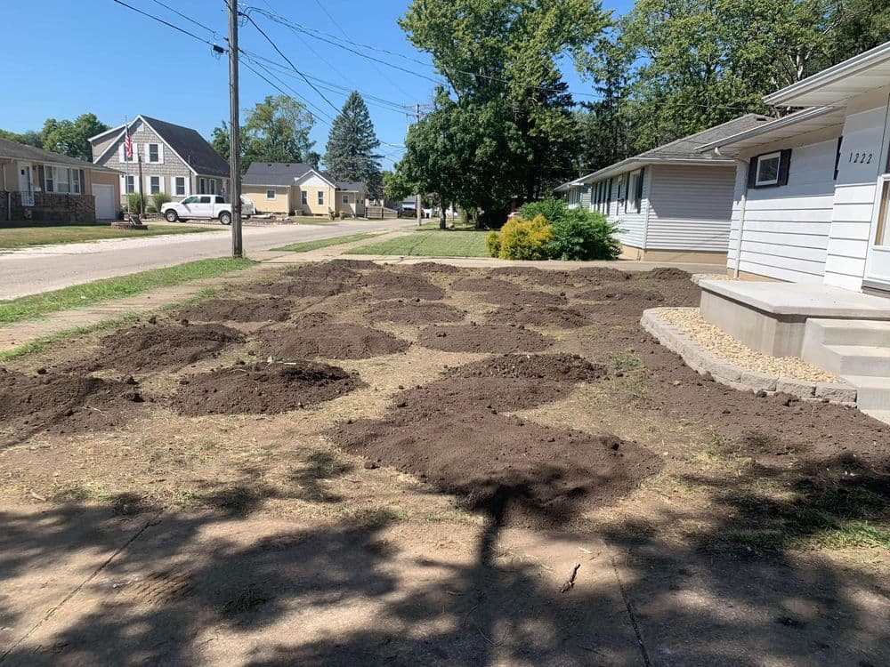 Ground preparation with mounds of dirt for landscaping in a residential area.