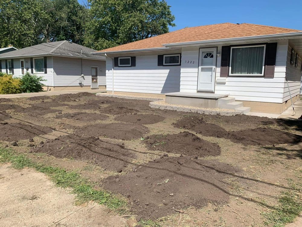 House with newly prepared garden beds in front yard, ready for planting.