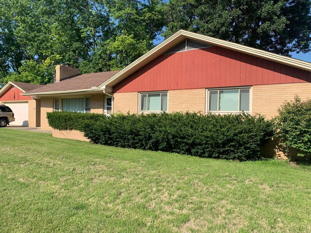 Front view of a suburban house with red accents, brick facade, and well-maintained lawn.