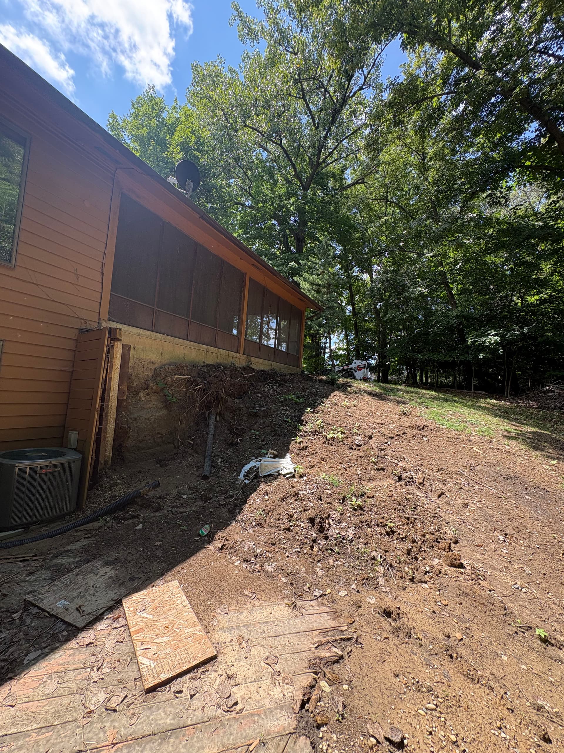 Retaining Wall and Drainage Fix Along a Sloped House Foundation image